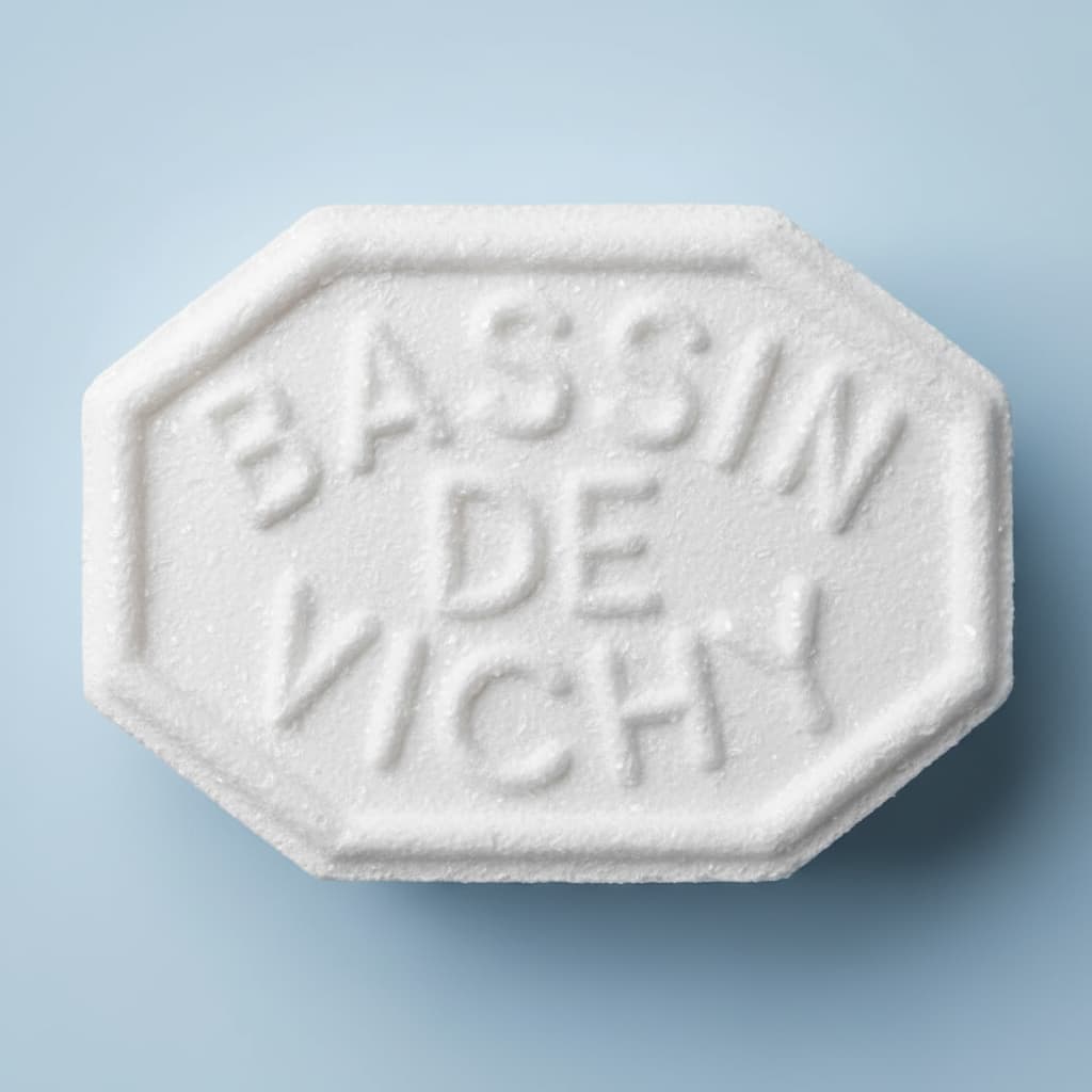 Gros plan macro d'une pastille de Vichy octogonale à la surface cristalline détaillée devant un fond dégradé bleu clair flou.