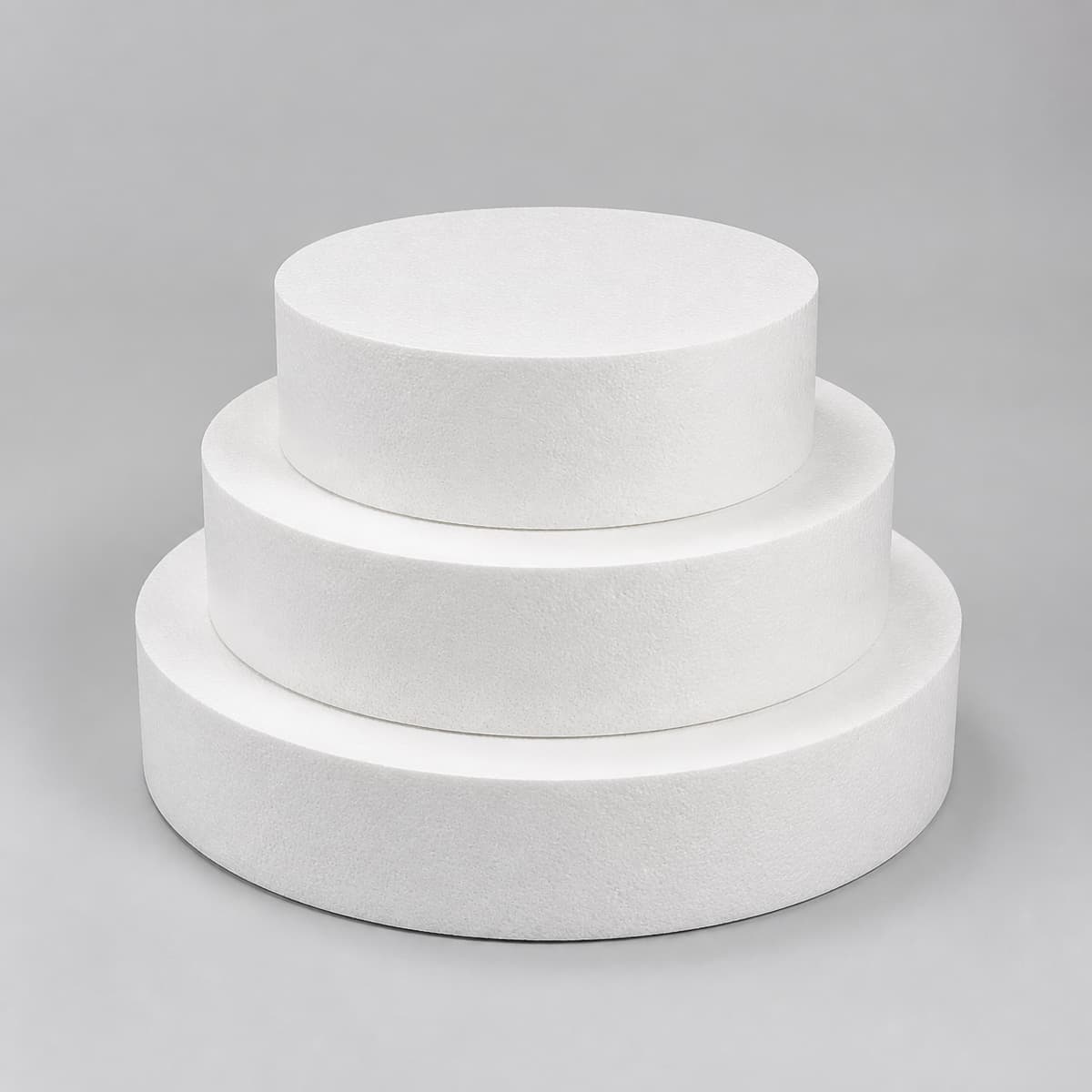 Support blanc en polystyrène composé de trois disques superposés de diamètres décroissants, vu de face en légère plongée sur fond neutre.