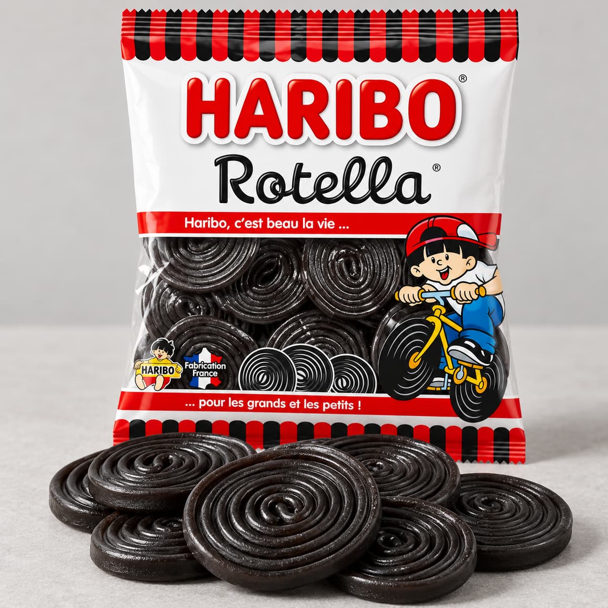 Emballage Haribo Rotella posé derrière plusieurs rouleaux de réglisse à spirales visibles sur fond neutre.